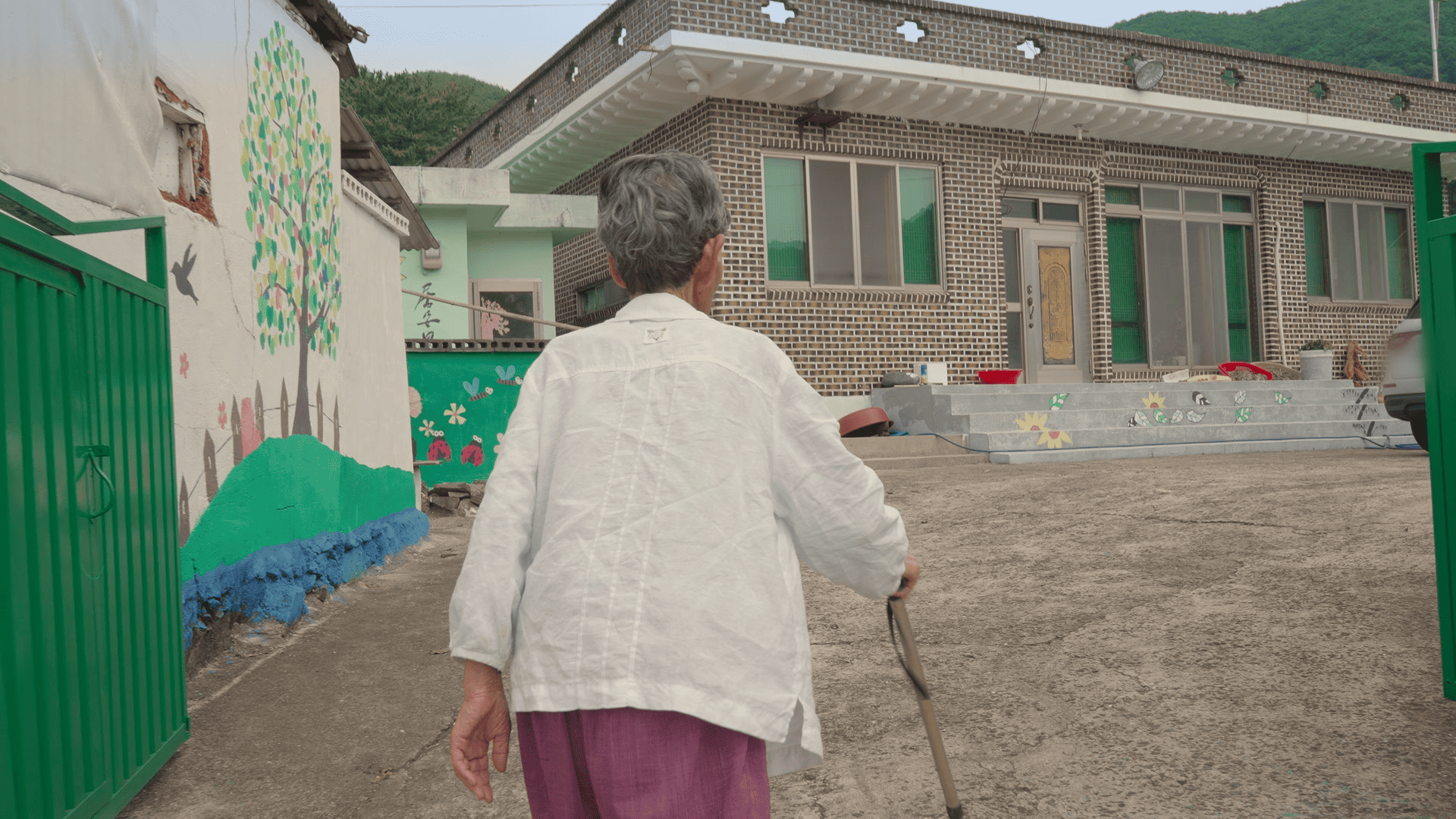 An older person is walking toward the entrance of a building.