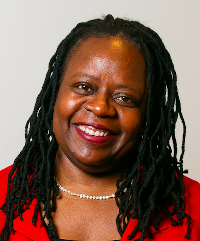 Dark brown-skinned Black woman with long dreadlocks and a wide smile.