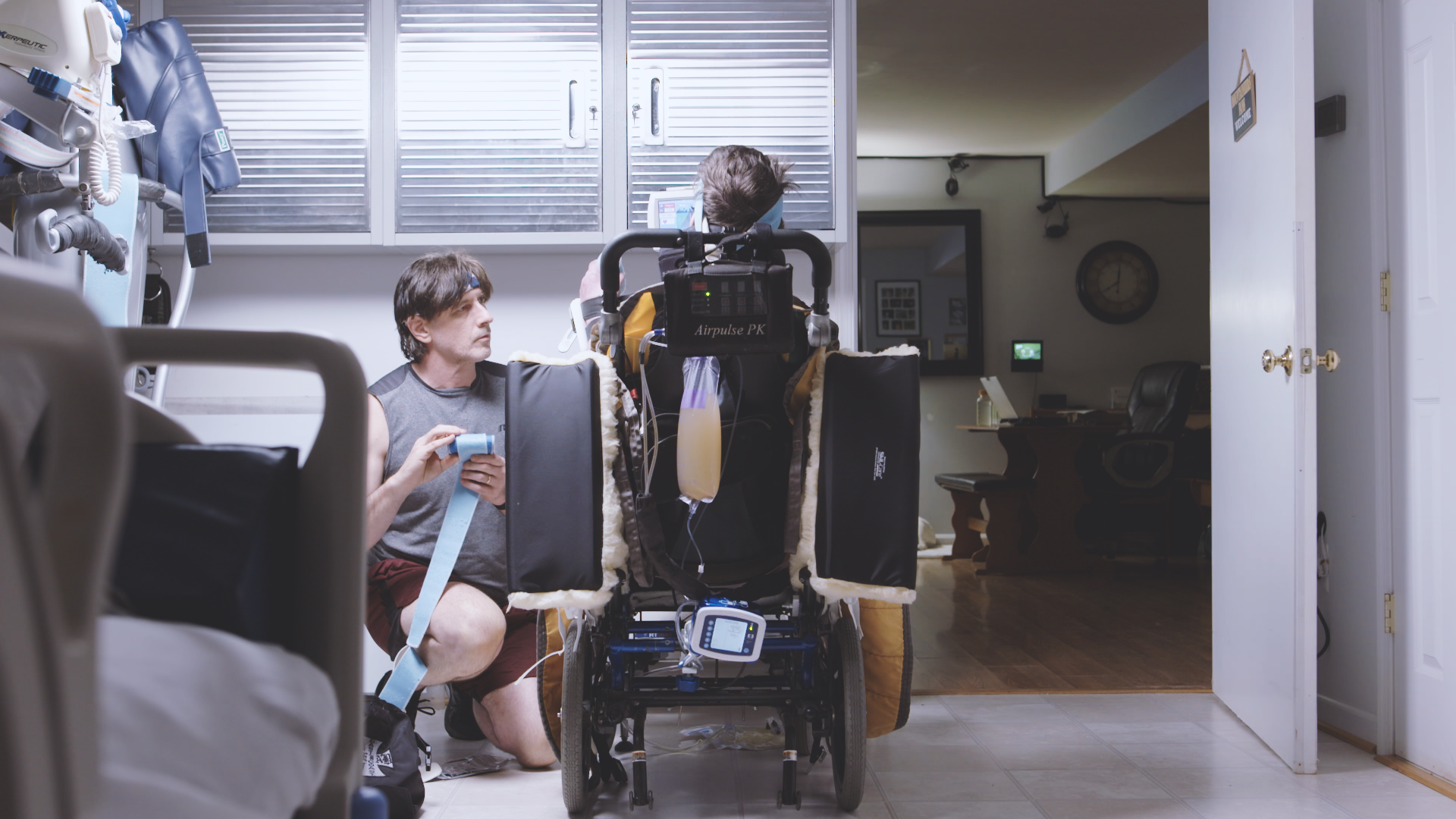 A person is kneeling next to a person in a wheelchair.