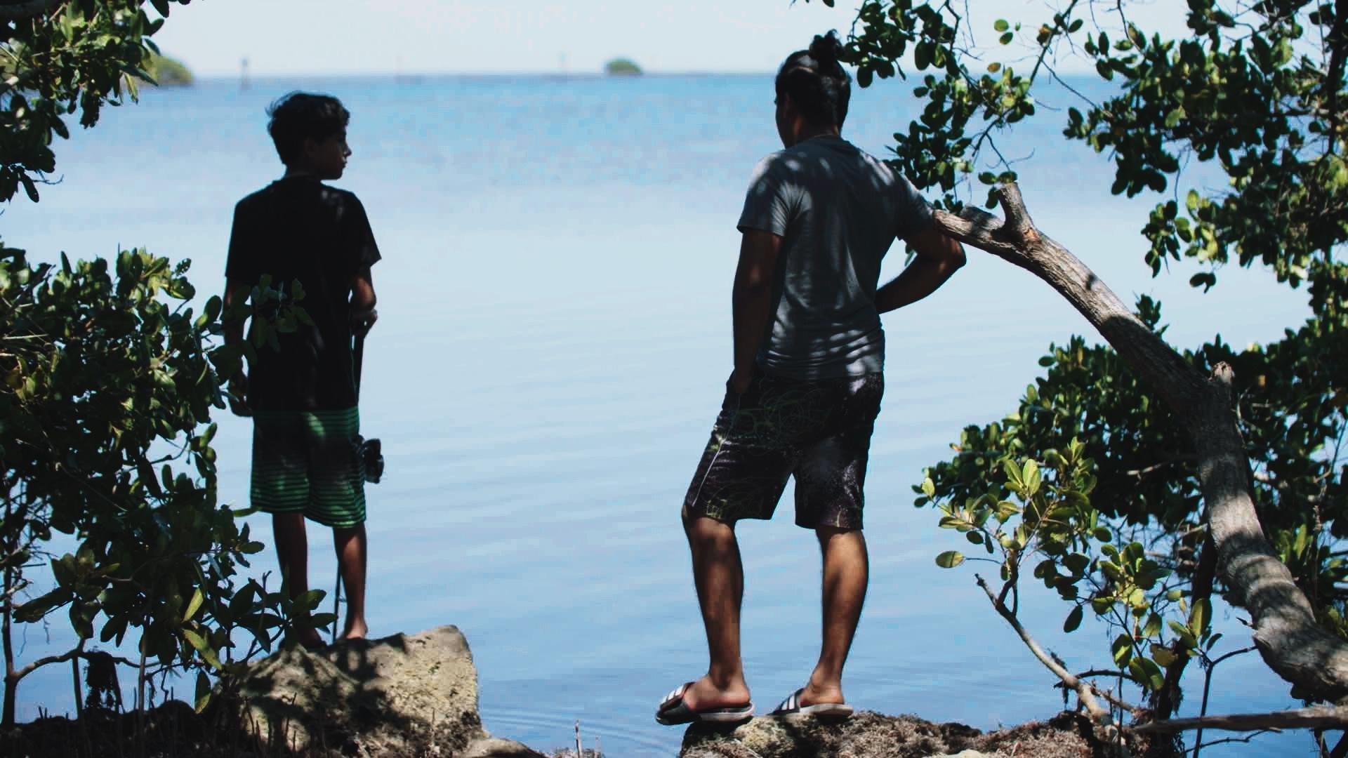 Still from Paper Children. Two brothers stand looking at a lake together.