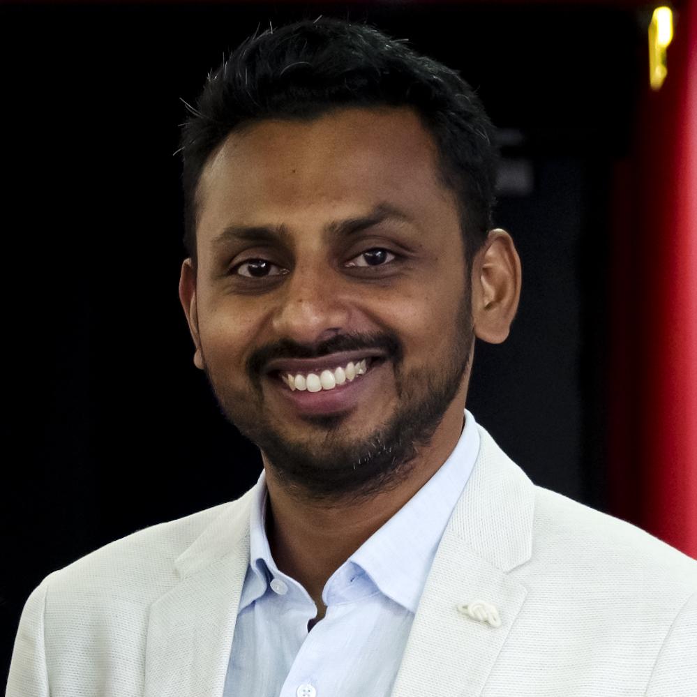 Headshot of Amit Madheshiya- he has black hair and is wearing a blue shirt with a white coat.
