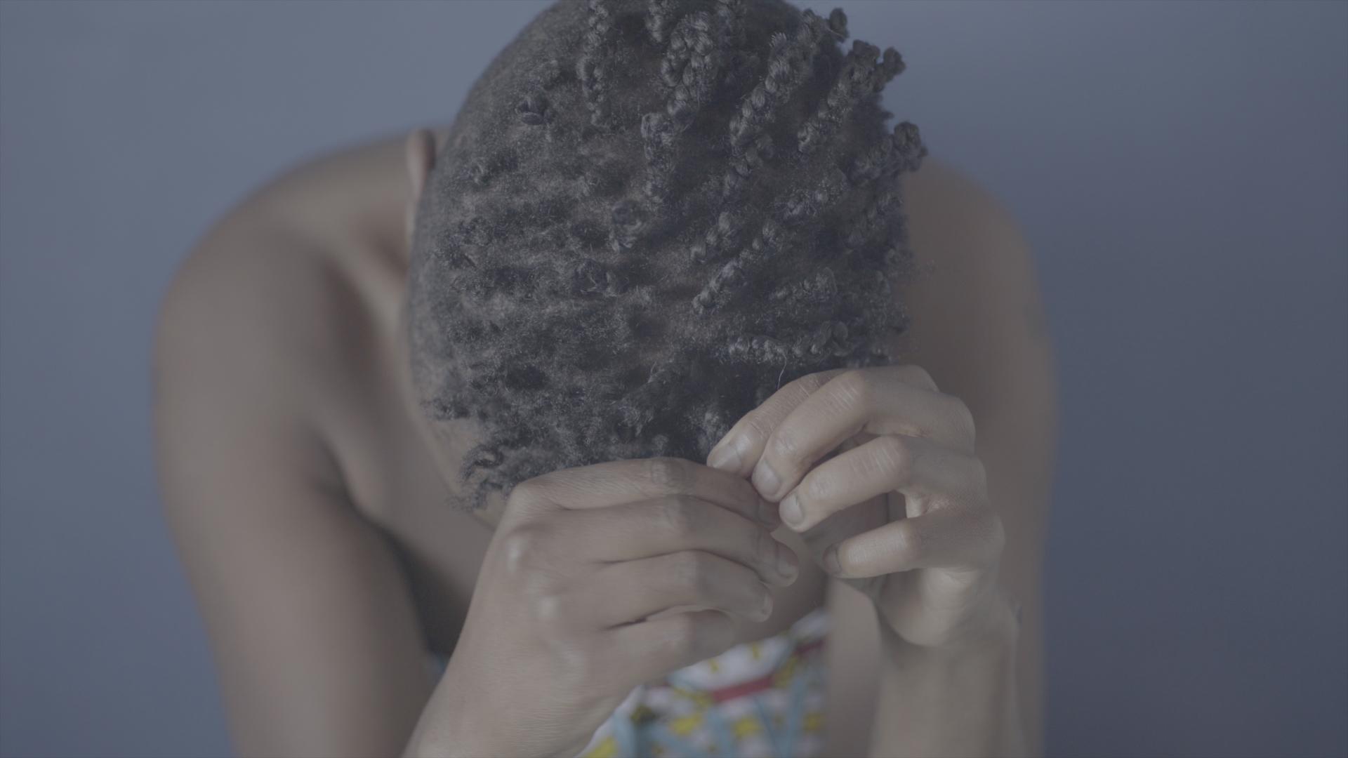 Still from Milisuthando. Aerial shot of a person braiding their hair.