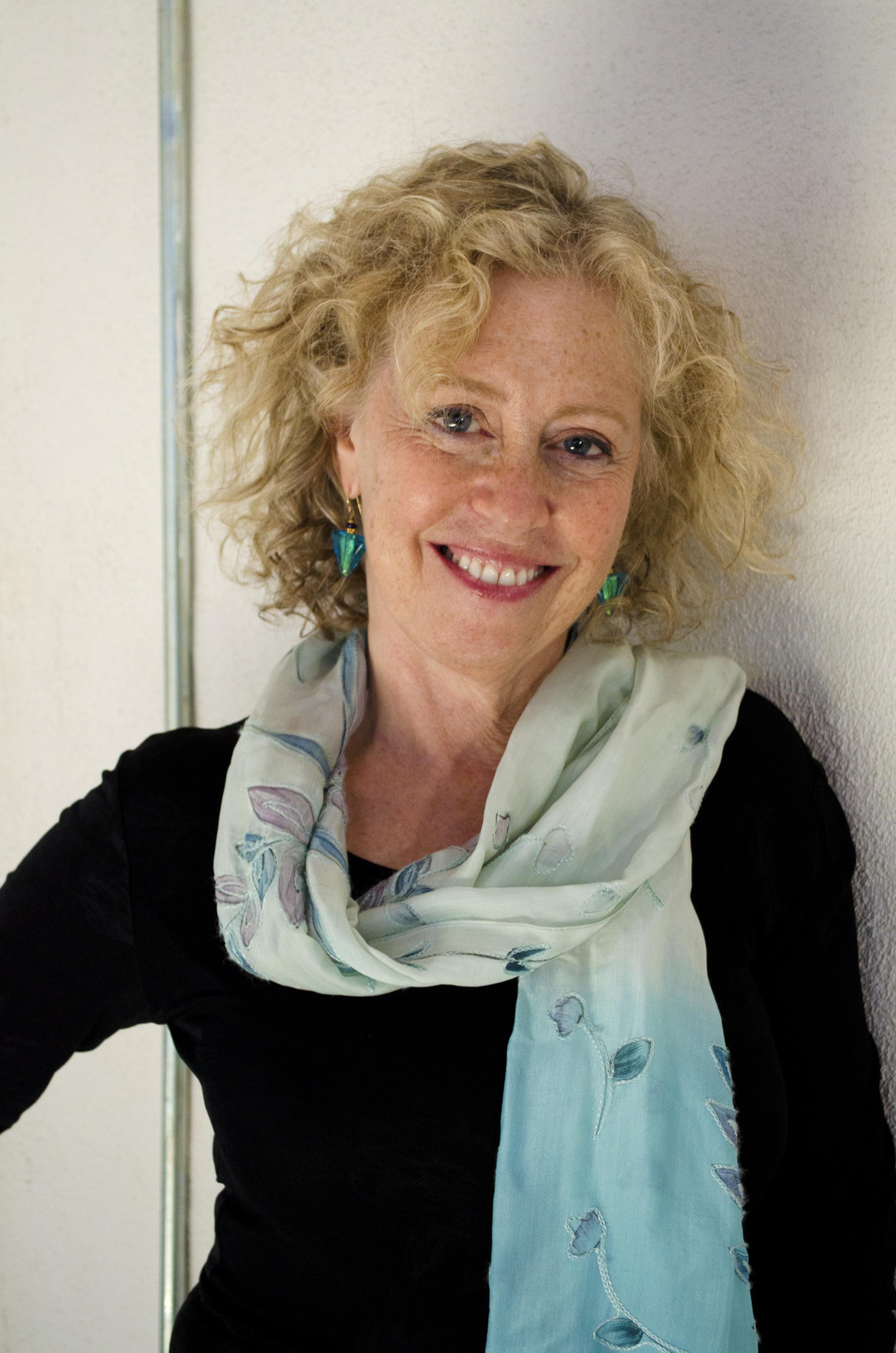 Photo of Lisa Fruchtman looking directly at the camera with a blue scarf on.